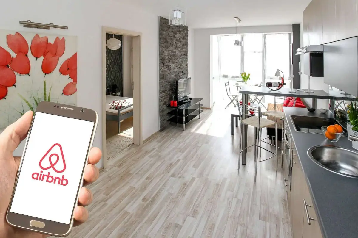 A Budapest apartment furnished for short-term letting, with a phone showing the Airbnb app in the foreground