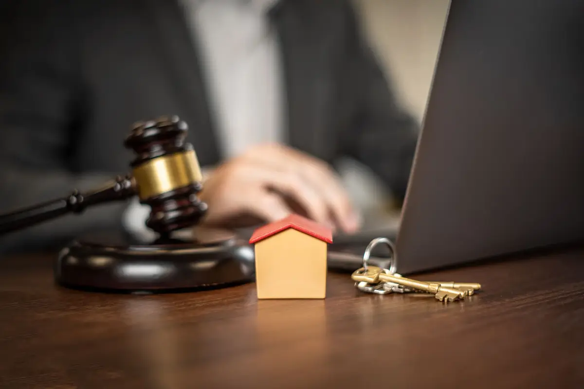 Property sale on a desk: keys, a house model and a laptop