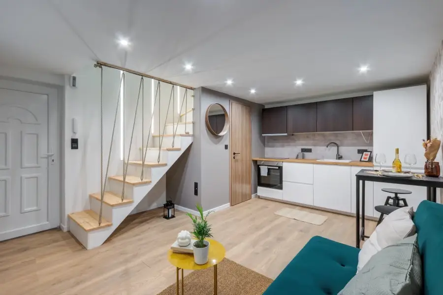 Interior of a renovated two-level apartment: open kitchen, dining area and mezzanine stairs