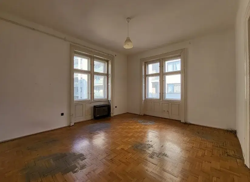 An empty Budapest apartment with tall windows, before renovation